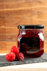 jar of raspberry jam with berries on a wooden background