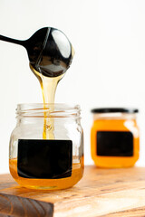 honey flows from a spoon into a jar