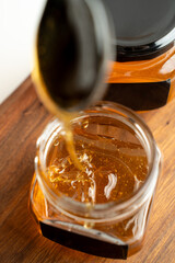 honey flows from a spoon into a jar