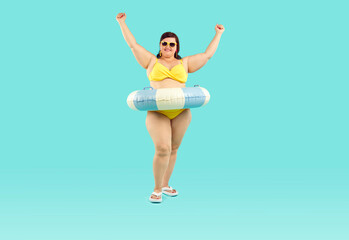 Happy funny fat plus size overweight woman in sunglasses with rubber ring wearing yellow swimsuit...