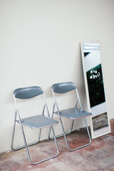 Two metal chairs next to a mirror.