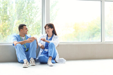 Young doctors sitting in hall of clinic - obrazy, fototapety, plakaty