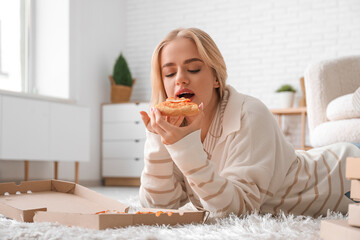 Young beautiful woman eating tasty pizza at home