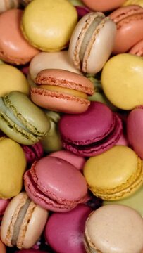Top view of rotating fresh macaron cookies. Traditional french desserts from almond dough. Slow motion of colourful sweet macaron cakes spinning in a bakery shop. French cuisine or sweets concept.