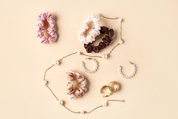Silk scrunchies with earrings and necklace on beige background