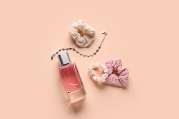 Bottle of perfume with bracelet and scrunchies on beige background
