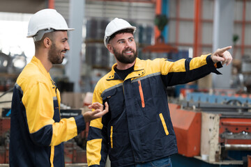 Two male engineers workers working in factory. Male workers discussing together in factory