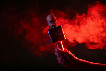 Woman with modern microphone and red smoke on dark background