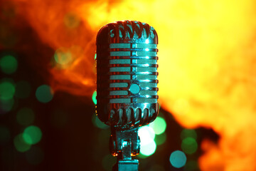 Retro microphone and flame against blurred lights, closeup
