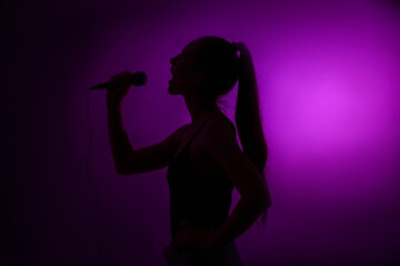 Silhouette of woman with modern microphone singing on dark background - obrazy, fototapety, plakaty