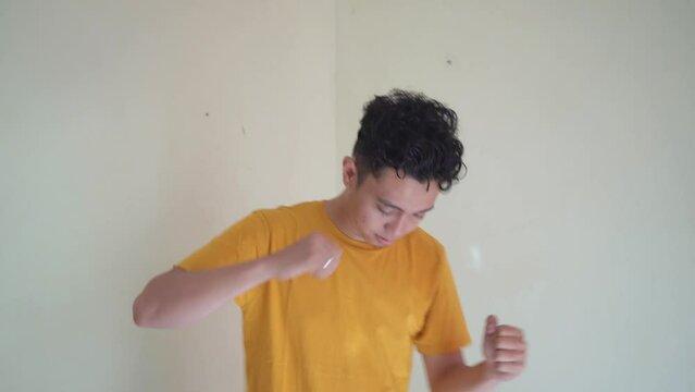 Young Indonesian curly man wear yellow t-shirt with singing gesture. The footage is suitable to use for man expression and people advertising content media.