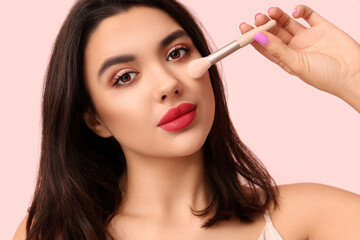 Obraz premium Beautiful young woman with stylish makeup and brush on pink background