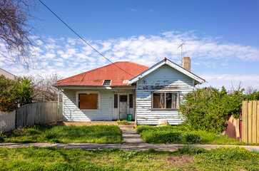 An old, neglected, and shabby residential house with an unattended front yard. An abandoned...