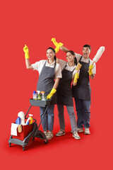 Workers of cleaning service with supplies on red background