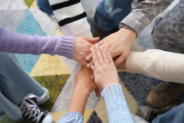People putting hands together at group therapy session, closeup