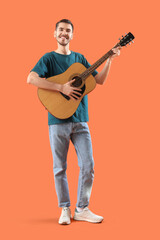 Naklejka premium Handsome young man with guitar on orange background