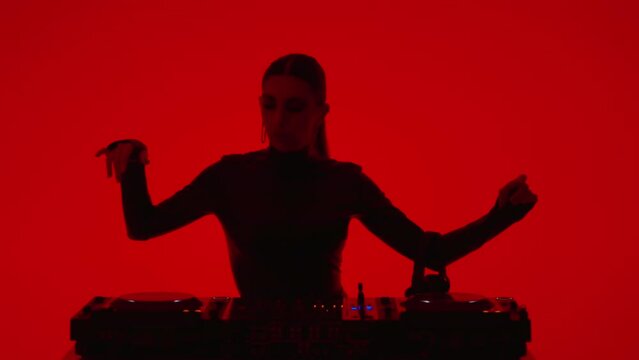 Sexy Lady DJ Mixing Electronic Tracks In Studio With Red Background, Medium Portrait Shot