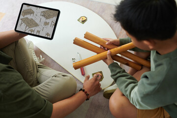 Father and son examining manual on tablet computer when assembling small table