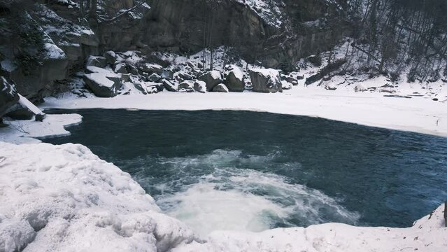 Winter mountain river under ice. Water froze and turned into icicles.