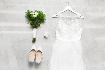 Wedding composition with dress, shoes, bouquet and ring box on grey tiles background