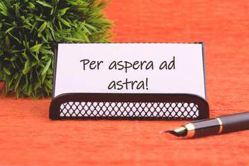 Per aspera as astra in English means through hardships to the stars on a white business card on an...