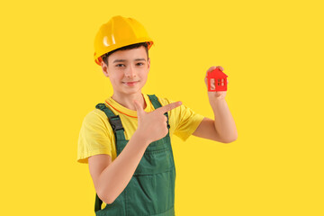 Little architect pointing at house figure on yellow background