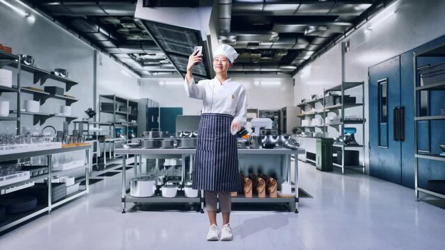 Full Body Of Asian Woman Chef Using Smartphone Taking Picture In Professional Kitchen