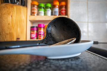 Soup leftovers on black plastic ladle on kitchen tabletop