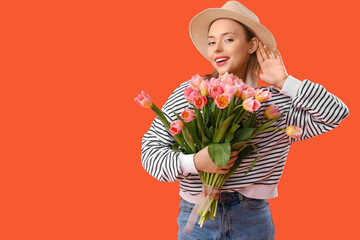 Young woman with hearing aid and tulips on orange background. International Women's Day - obrazy, fototapety, plakaty