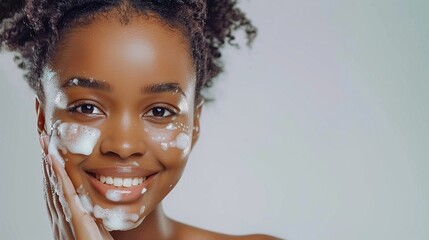 An African American woman with clear skin washing her face with soap on a grey background