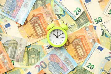 Many European euro money bills and alarm clock. Lot of banknotes of European union currency close up