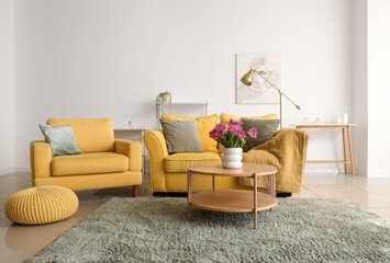 Interior of light living room with sofa, armchair and tulips on table - obrazy, fototapety, plakaty