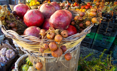 Close-up of a wicker basket full of fresh, ripe pomegranates at a market stall in Rome, Italy