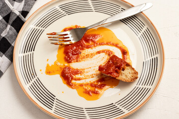 Dirty plate with remains of red tomato sauce. Close up, top view.