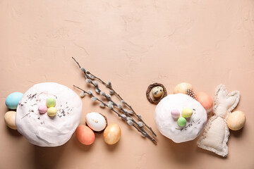 Easter cakes, toy bunny, willow branches and painted eggs on beige background