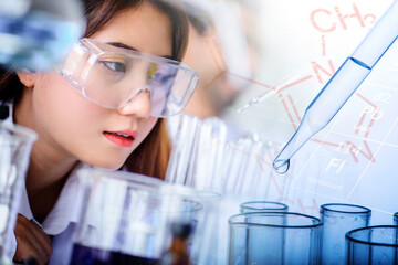 Attractive scientist woman testing chemical sample in flask at laboratory with lab glassware background. Science or chemistry research and development concept