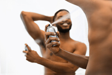 Shirtless man applying deodorant on body in bathroom