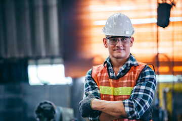 Portrait of male foreman factory wearing hardhat in arms crossed looking at camera standing at the...