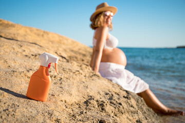 Pregnant woman wearing a sun hat during her walk on the beach relaxing on her summer vacation,...