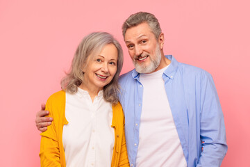 Cheerful senior man and woman in casual sharing embrace, studio