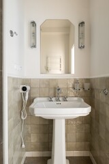Bathroom with pedestal sink, mirror, and hair dryer