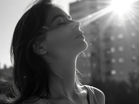 A woman is standing outside in the sun, looking up at the sky. She is wearing a necklace and earrings