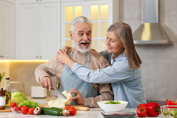 Happy senior couple cooking together in kitchen