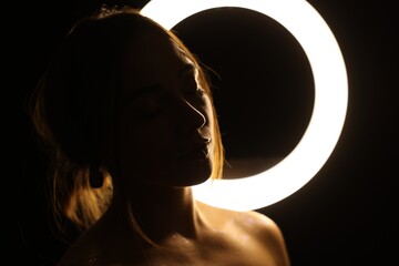 Beautiful woman and ring lamp in darkness