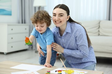 Mother and her little son painting with palms at home