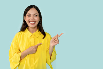 Happy Young Woman Pointing Aside At Copy Space on Blue Background 