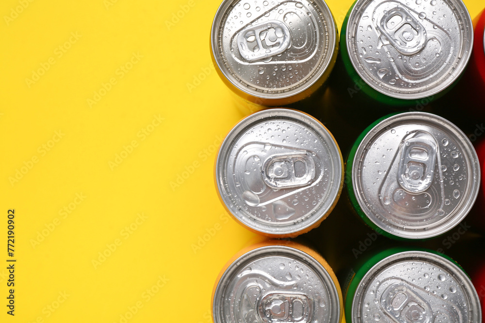 Wall mural Energy drinks in wet cans on yellow background, top view. Space for text