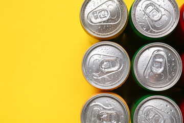 Energy drinks in wet cans on yellow background, top view. Space for text