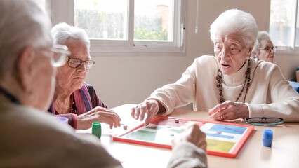 Senior woman playing ludo with friends at table in nursing home