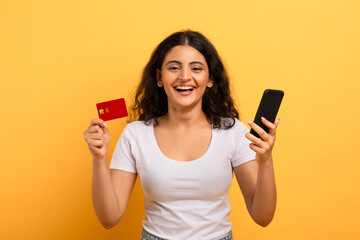 Naklejka premium Cheerful woman holding phone and credit card